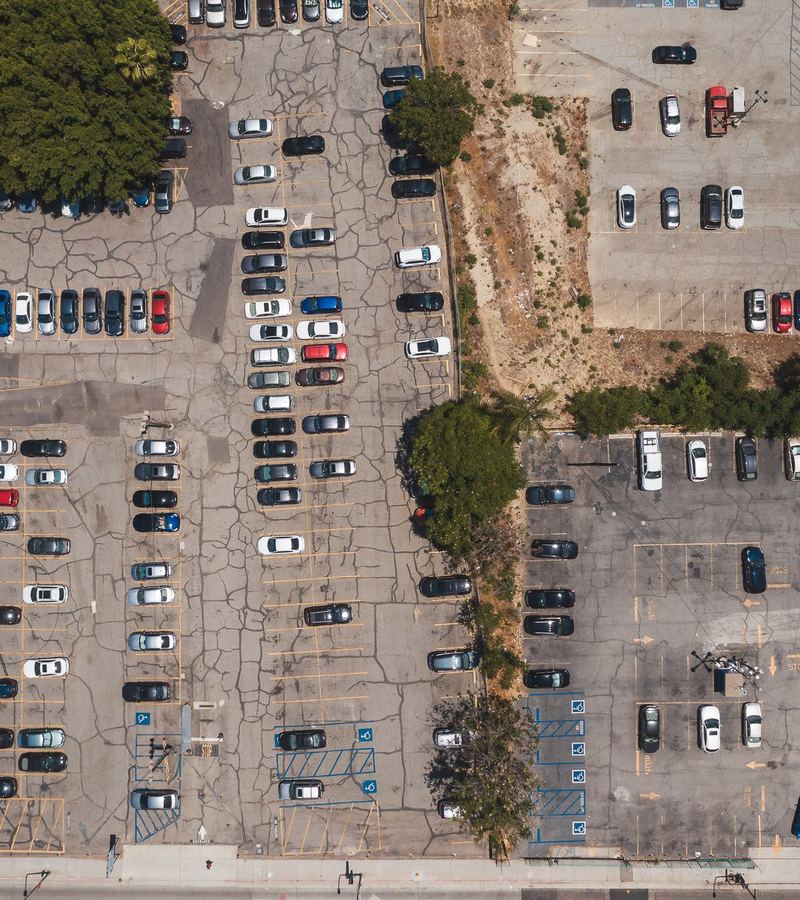 Luftaufnahme eines großen, geordneten Parkplatzes mit vielen abgestellten Autos