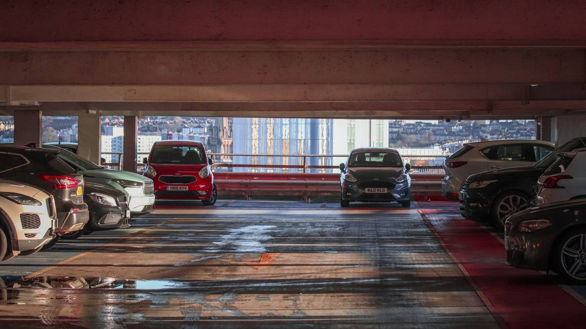 Geparkte Fahrzeuge in einem mehrstöckigen Parkhaus mit Blick auf die Stadt.