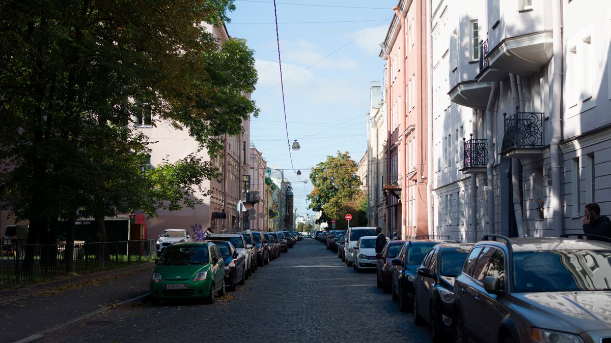 Ruhige Straße mit geparkten Autos bei Tageslicht.