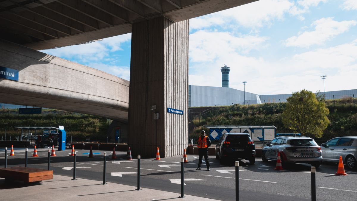 Fahrzeuge an einer Flughafen-Terminalvorfahrt mit Verkehrsleitkegeln.